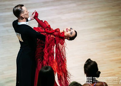 Dva tanečníci předvádějí elegantní tanec na soutěži Brno Open 2026, s publikem v pozadí, v elegantním oblečení, na parketu.