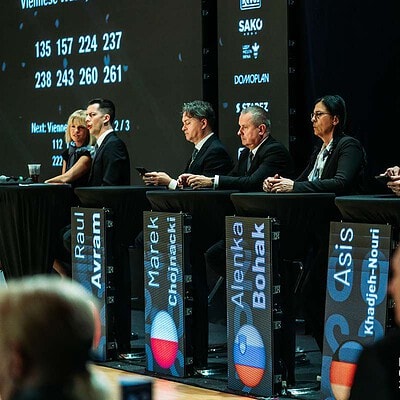 Mezinárodní šachový turnaj BrnoOpen 2026 s mezinárodní účastí a soutěžícími na pódiu, zázemí a diváky v pozadí.