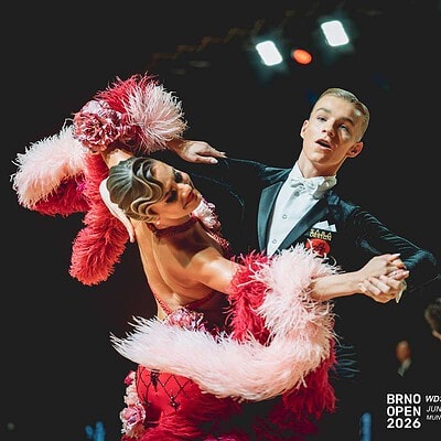 Dva tanečníci v elegantním oblečení během soutěže Brno Open 2026, předvádějí složitou taneční choreografii na parketu s profesionálním osvětlením.