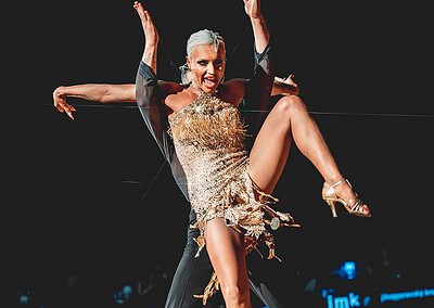 Dva tanečníci předvádějí složitou taneční choreografii na soutěži Brno Open 2023, s výraznými pohyby a elegantními kostýmy.