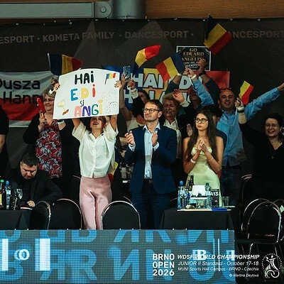 Skupina lidí na sportovní akci BrnoOpen 2026, někteří drží transparenty a oslavují úspěch, v pozadí vlajky a logo akce.